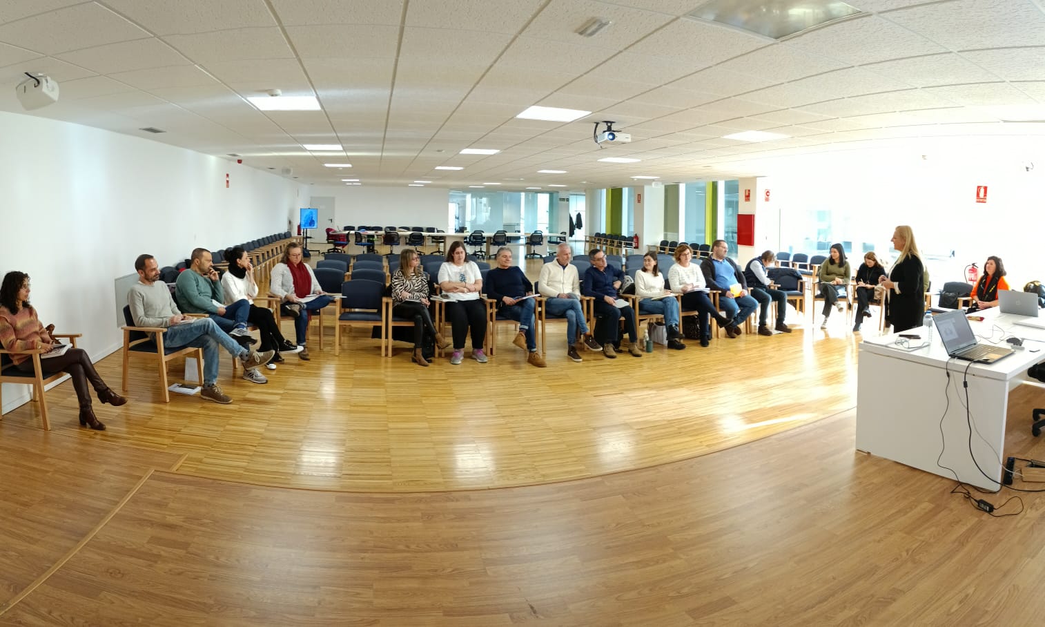 Fotografía de sala con personas sentadas en círculo participando en actividad grupal